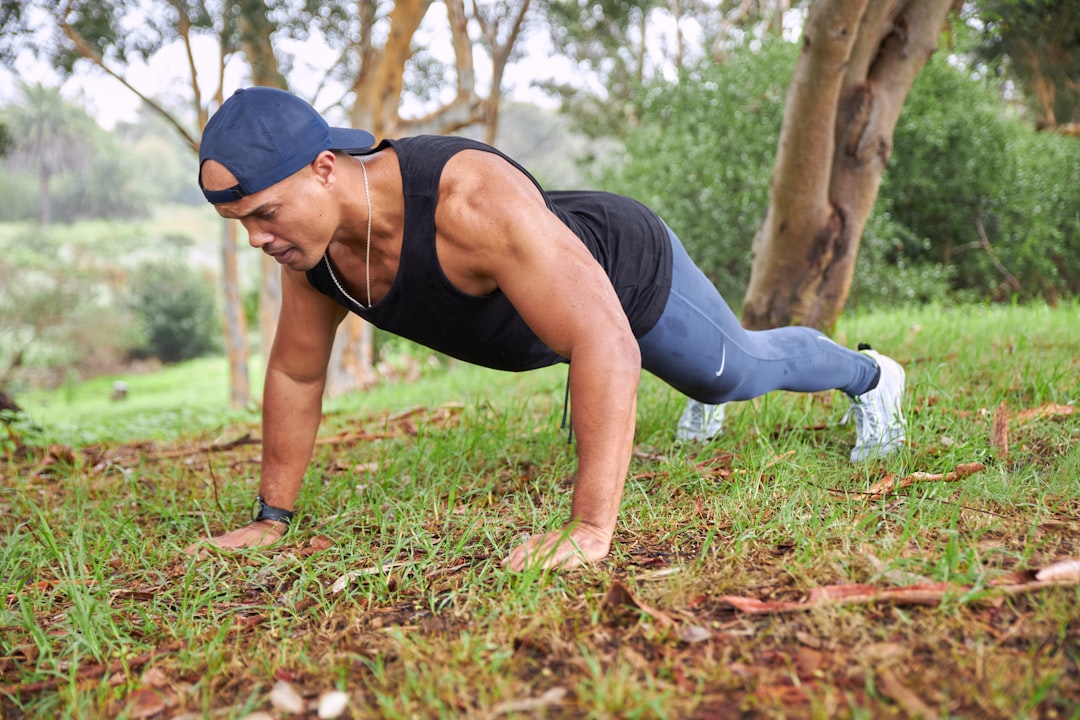 Homem fazendo flexão de braço na grama, um dos exercícios para perder barriga mais multiarticulares e eficientes